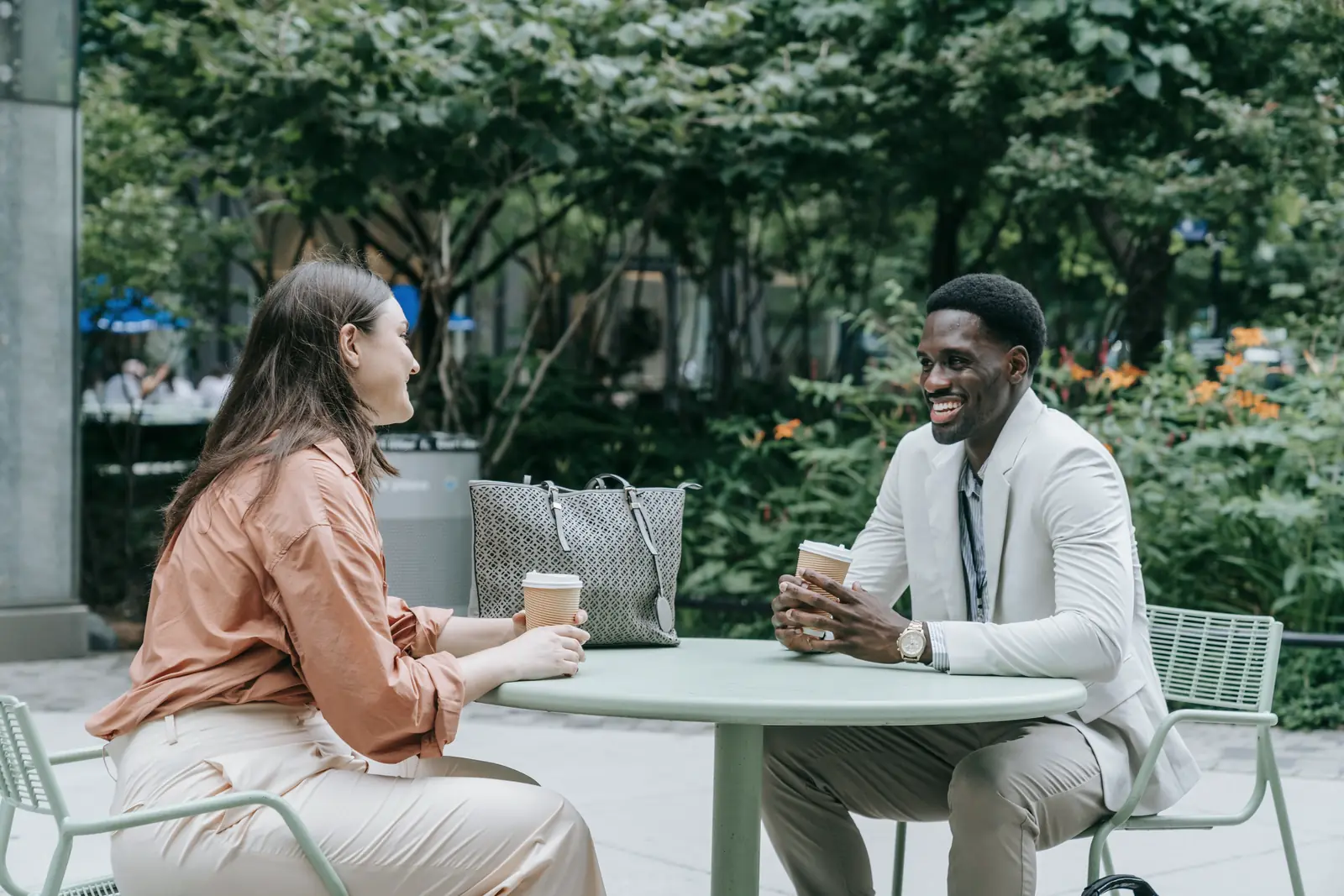 Zwei Personen sitzen im Gespräch an einem Café-Tisch.
