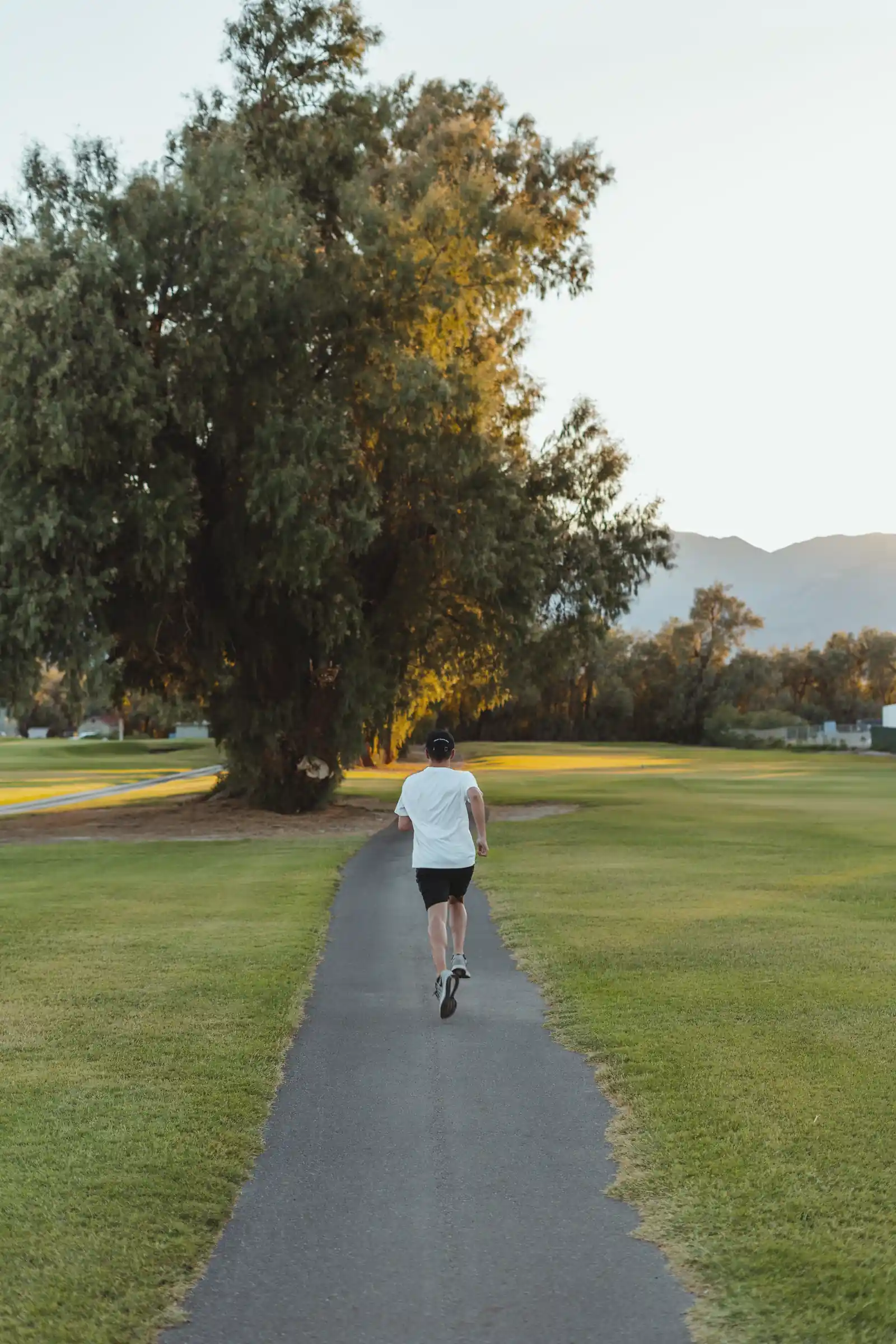 Frau joggt an einem sonnigen Morgen auf einem Weg im Park.