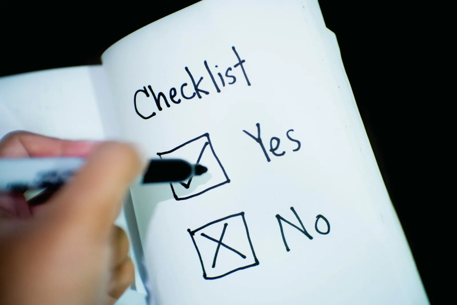 Aufgeschlagenes Buch mit abgehakter Checkliste und Bleistift.